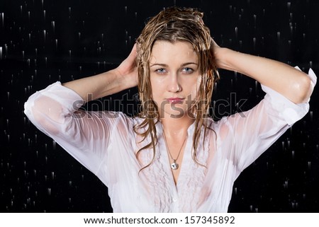 Wet girl with serious face under the spray of water