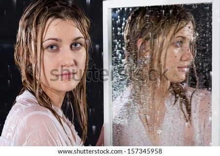 Portrait of girl with wet hair under the spray of water near the mirror