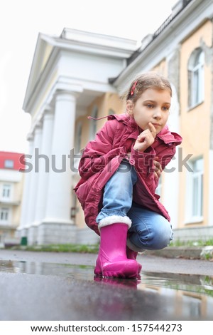 A girl with a thoughtful expression on her face squatted on street