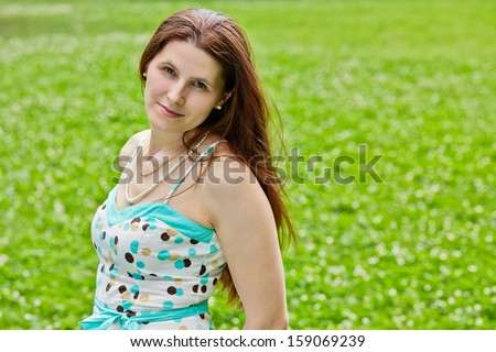 Half-length portrait of chestnut-haired woman on sunny grassy lawn