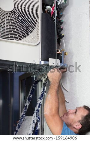 A worker sets split system air conditioner outdoor