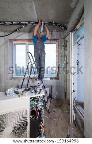 A worker sets tubes for split system air conditioner indoor