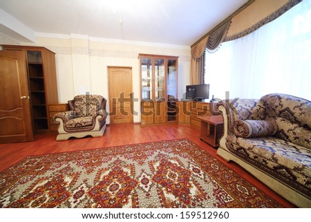 Living room with sofa, chairs, sideboard and a carpet on the floor