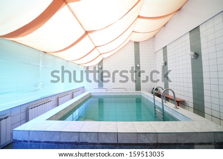 A Small Indoor Pool With Tiles On Walls And Floor And Blinds On The Windows