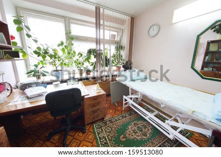 Interior of a light doctors consulting room with a bed and a workplace