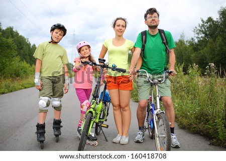 Active rest on nature of the family of four with roller skates and a bicycles