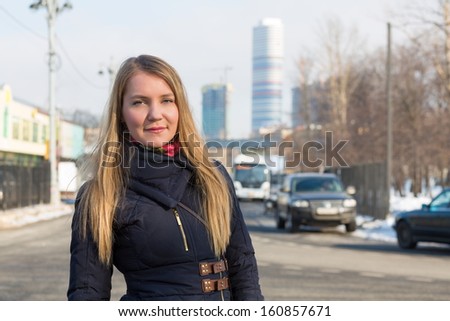 The girl in warm clothes on the street on the background of skyscrapers
