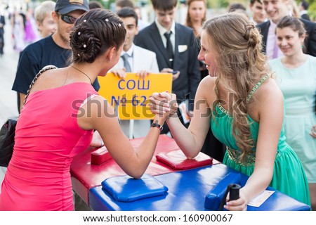 MOSCOW - JUN 23: The girls graduates in beautiful dresses are arm wrestling on the street on June 23, 2013 in Moscow, Russia.