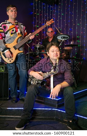 The musical group of three men on stage in a club