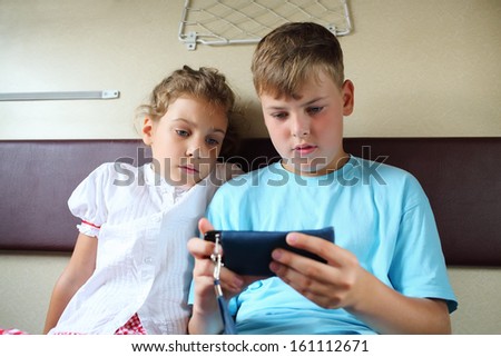 Brother and sister playing with the phone and watching a movie while traveling in train