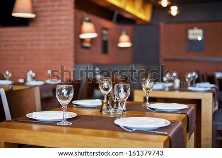 Room with served tables in restaurant, focus on glass in center