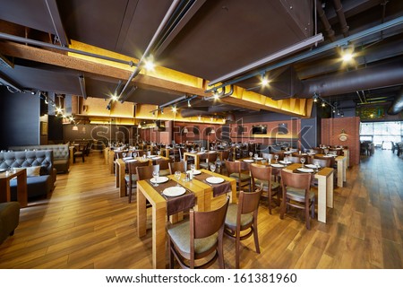 Interior Of Restaurant With Wooden Furniture And Walls Of Red Bricks