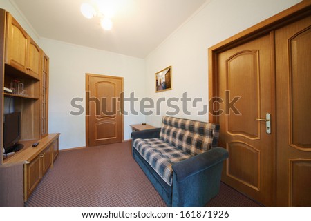 Small living room with a blue checkered sofa, wall cabinet and TV