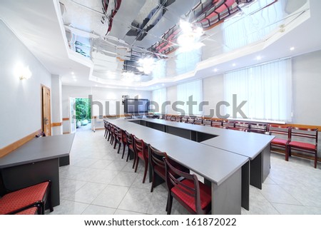 Modern interior of empty meeting room with conference table and red chairs