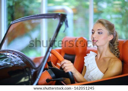 A young woman driving a retro black car