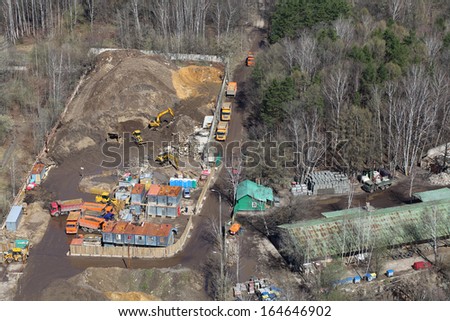 Top view of small construction site with many trucks and machinery in woods.
