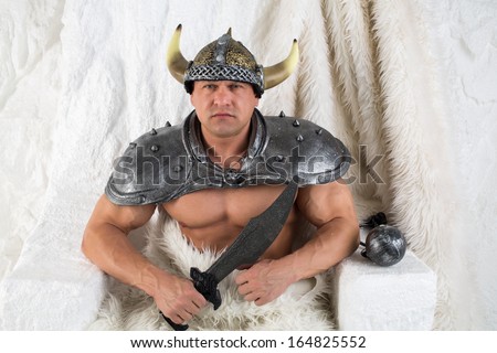A muscular man in costume viking and fur with a sword