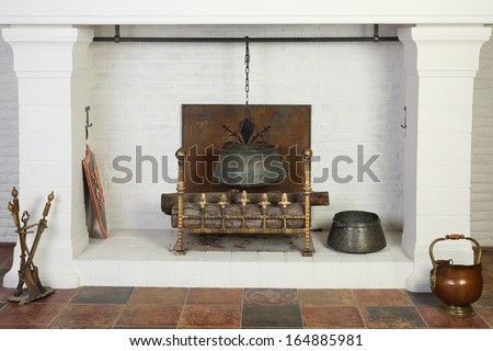Medieval white fireplace with hanging metal pot and logs in studio.