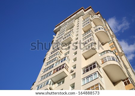 New high residential building with balconies and windows on background of blue sky.