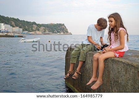 A young boy and girl fishing in the sea with a fishing rod