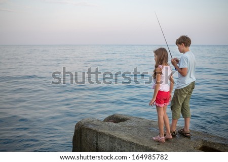 A young boy an girl with a fishing rod fishing in the sea