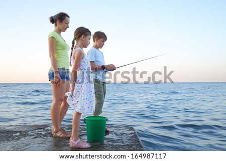 Family of three with a fishing rod fishing in the sea