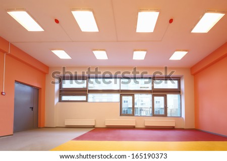 Empty gym with orange walls and large windows in the kindergarten