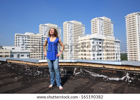Happy woman with raised up his head stands on roof of the building