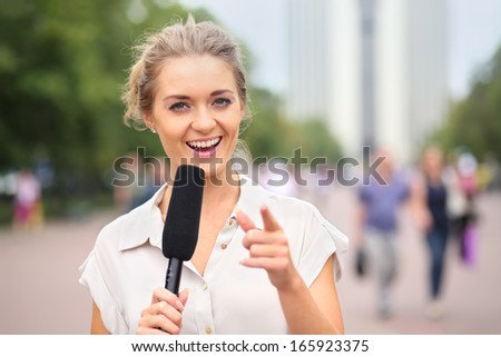 A Smiling Girl Reporter With Microphone In Hand On The Street