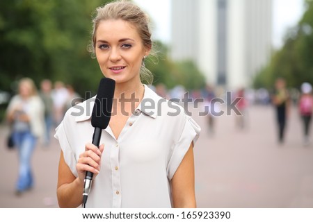 Professional reporter beautiful girl standing on the street with a microphone in hand