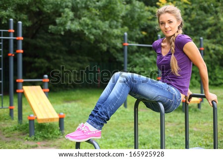 Young girl sitting on sports equipment on the outdoor sports ground