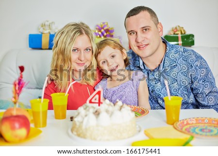 Happy family of three sits at birthday table