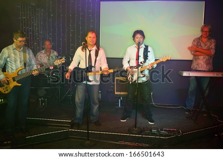 Five men with musical instruments performs on stage in a club