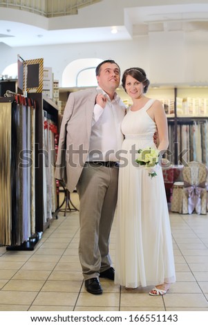 Beautiful bride and groom standing in a shop in the hall with samples of curtains