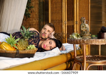 Beautiful woman and young man lie on bamboo bed and dream in bedroom.