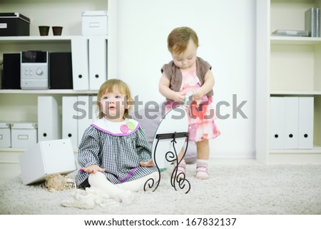 Two little girls play on white carpet with mirror and bead at home. Shallow depth of field. Focus on left kid.