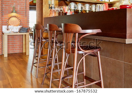 Three tall wooden stools at counter with beverages and glasses in cafe
