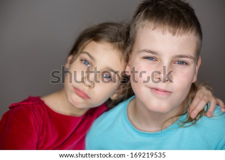 Portrait of sister and brother hugging in the studio, focus on a boy.