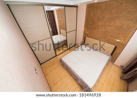 Modern bedroom with closet, large mirror and bed.