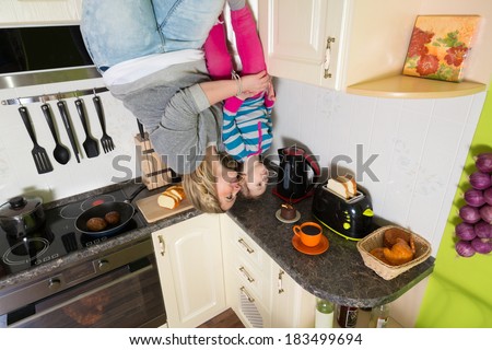 Mother with daughter stand upside down in the kitchen with toaster