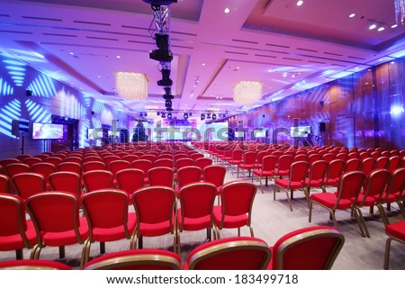 Conference  hall with red chairs and colored illumination