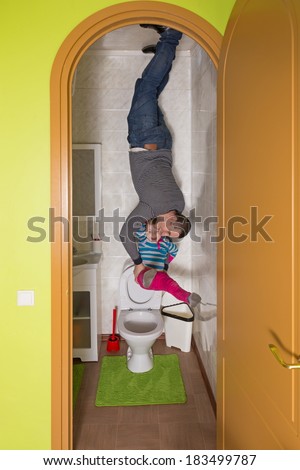 Father with daughter upside down on the ceiling in toilet at inverted house