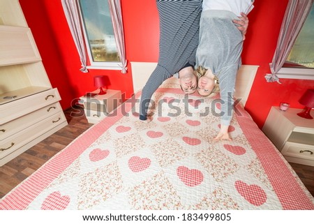 Man with a woman in an embrace stand upside down on the bed