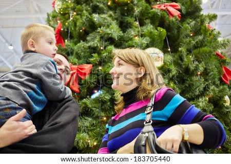 Mother, father with son in arms near christmas tree