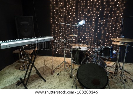 Studio room with keyboard, drum set and record equipment.