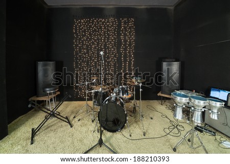 Studio room with drum set, microphones and recording equipment.