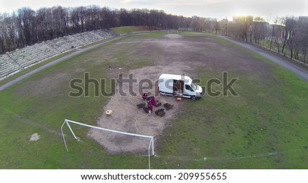 The workers prepare fireworks on an old football field outdoors, aerial view
