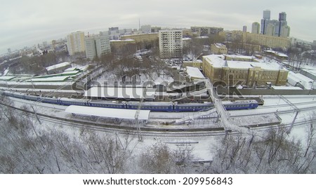 MOSCOW, RUSSIA - NOVEMBER 27, 2013: Train at snow-covered railway platform with a pedestrian bridge in the city, aerial view