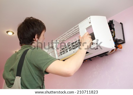 Worker installs grid on the air conditioner in the new apartment