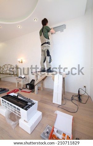 Worker installs a metal plate for fixing the air conditioner